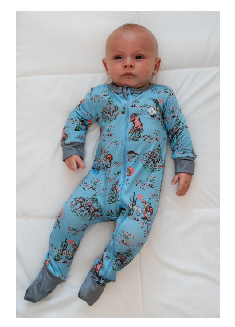 Baby wearing a blue onesie with animal prints on a white background