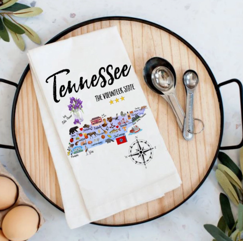 Towel with 'Tennessee' design on a wooden cutting board with measuring spoons and eggs.