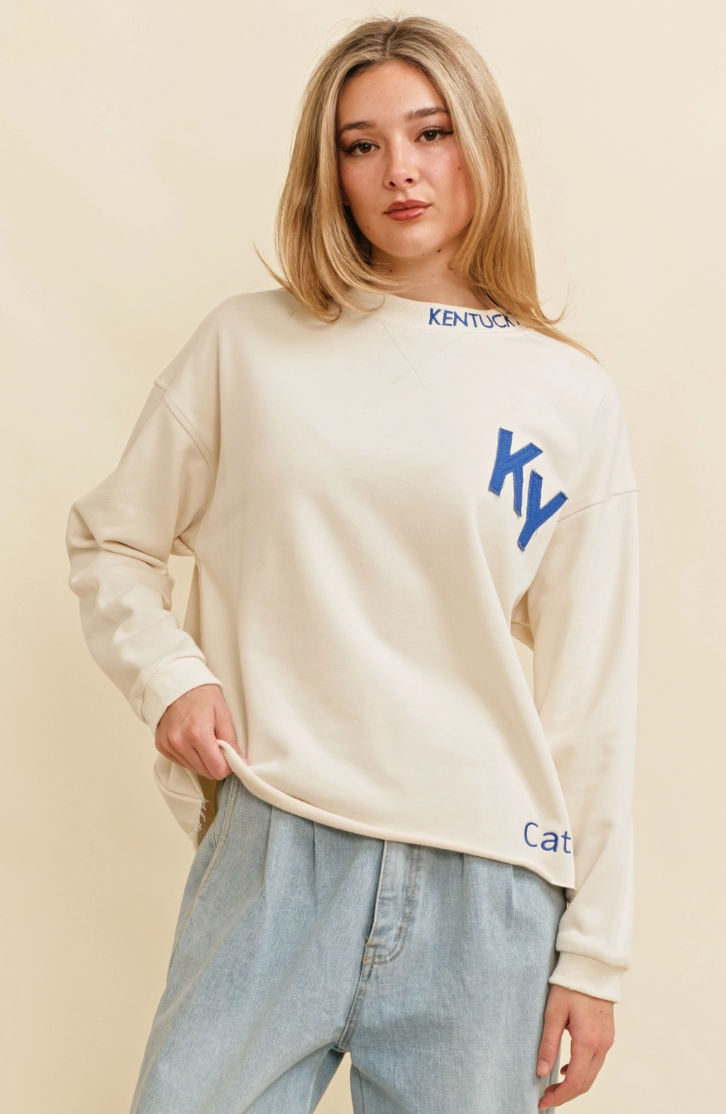 Person wearing a cream sweatshirt with blue text on a beige background