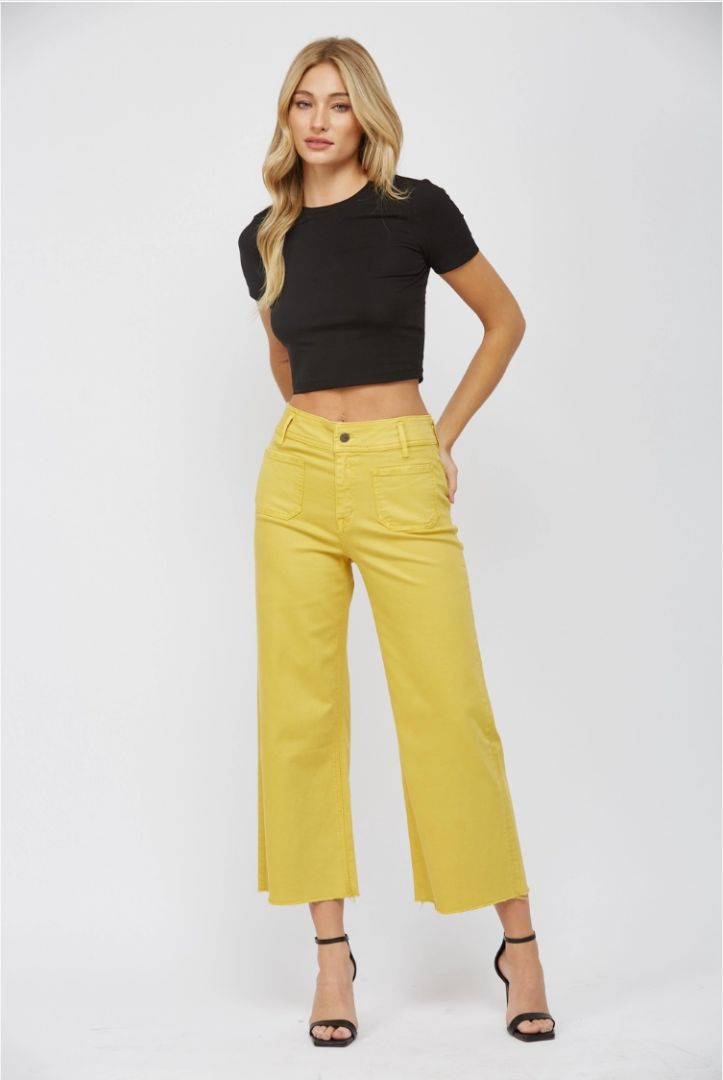 Woman wearing a black crop top and yellow pants on a white background