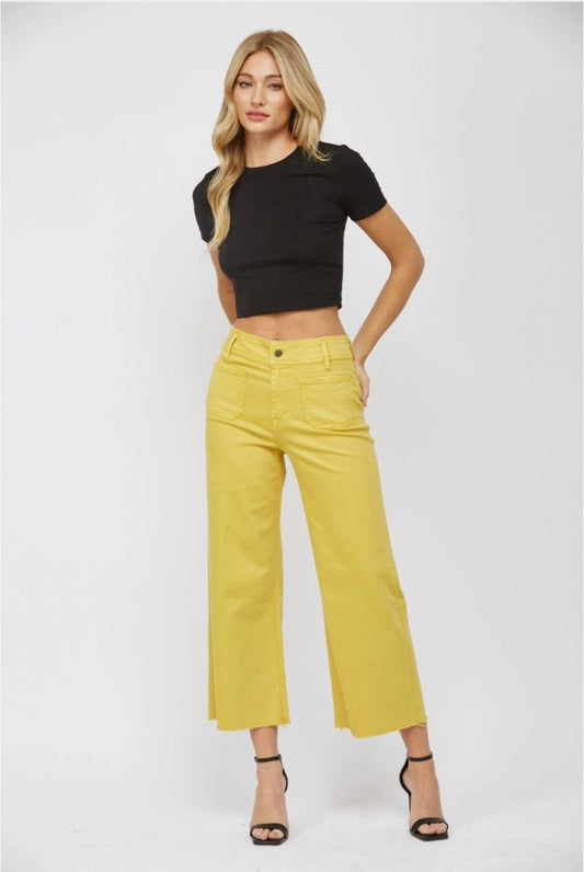 Woman wearing a black crop top and yellow pants on a white background