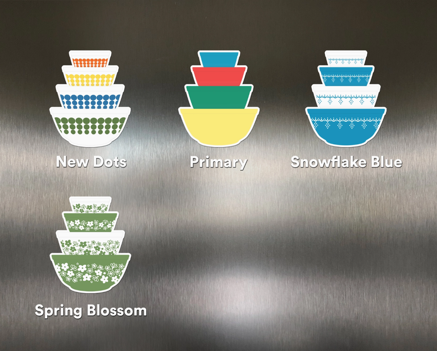 Set of colorful stacked bowls with labels 'New Dots', 'Primary', 'Snowflake Blue', and 'Spring Blossom' on a metallic background.