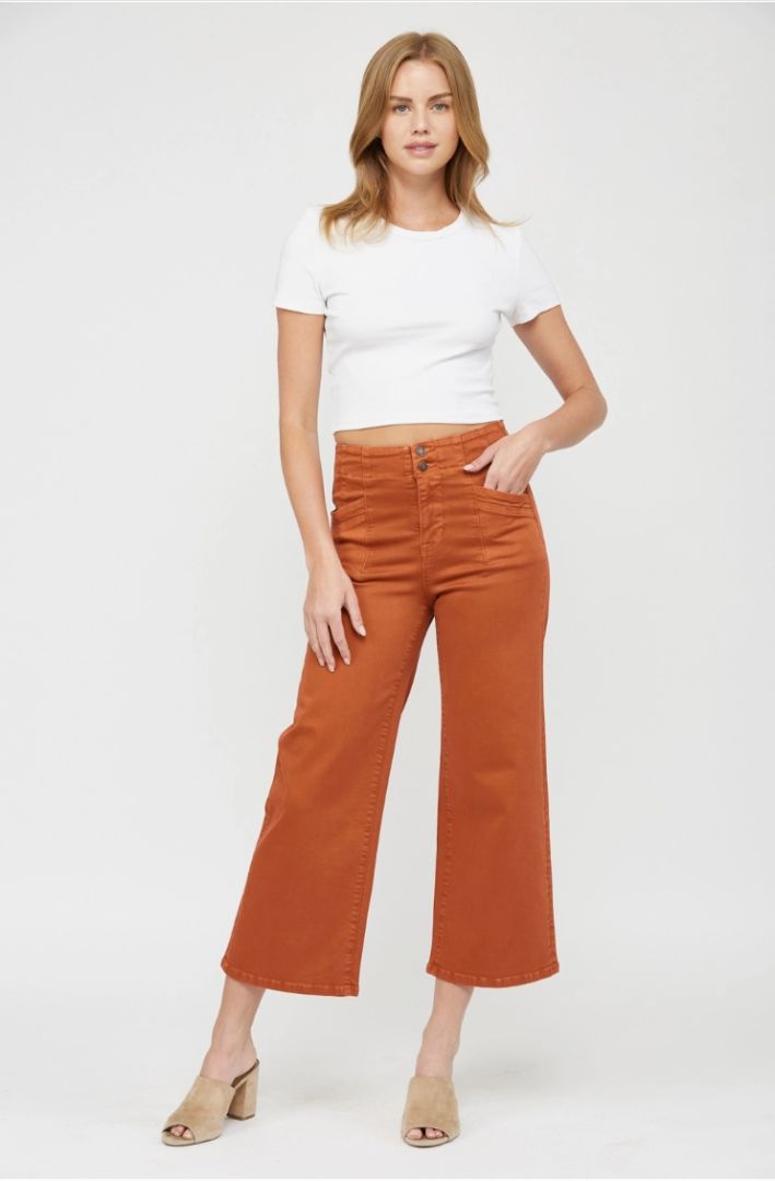 Woman wearing a white t-shirt and orange pants on a white background