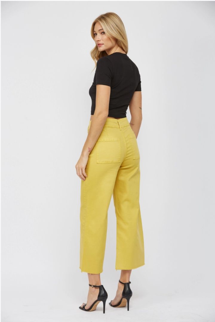 Woman wearing a black top and yellow pants on a white background
