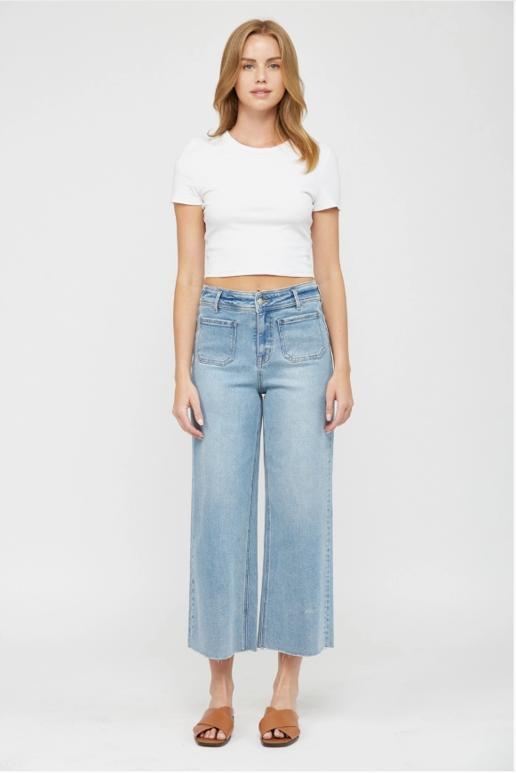 Woman wearing a white crop top and light blue wide-leg jeans on a white background