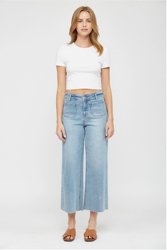 Woman wearing a white crop top and light blue wide-leg jeans on a white background
